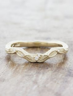 Bea is a twinkling bed of golden leaves that gently contours around an engagement ring for unbelievable natural beauty. Her leafy details lay one over another atop a hand-engraved bark textured band. Pairs perfectly with our June engagement ring. Leaf Detail Engagement Ring, Art Nouveau Engraved Rings For Wedding, Art Nouveau Style Gold Engraved Rings, Nature Inspired Engagement Rings Leaves, Leaf Engraved Wedding Band, Nail Goals, Wedding Band Designs, Golden Leaves, Curved Wedding Band