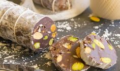 two pieces of chocolate with pistachio and almonds on a table next to a knife