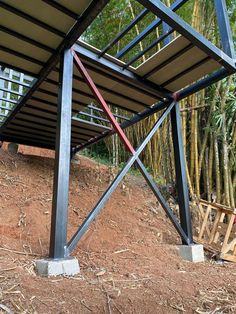 a metal structure sitting on top of a dirt hill next to bamboo trees in the background