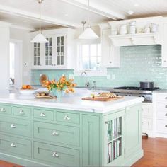 a kitchen with white cabinets and green island