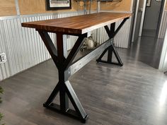 a wooden table sitting on top of a hard wood floor next to a metal frame