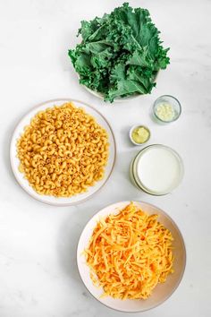 two bowls filled with pasta and cheese next to lettuce on a white table