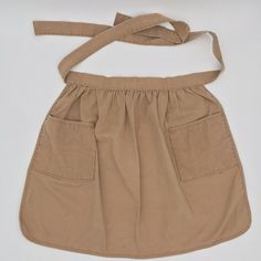 a tan skirt with a tie around the waist on a white surface, it appears to be worn by someone