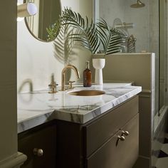 a bathroom with marble counter tops and a mirror over the sink that has a palm leaf on it