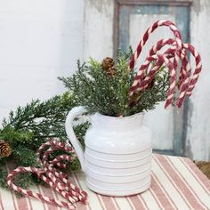 a white pitcher filled with candy canes on top of a table