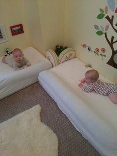 two babies laying on top of mattresses next to each other in a room with wall decals