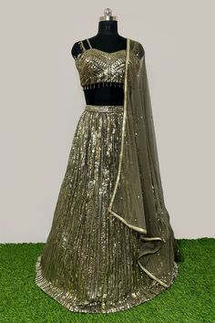 Description: - Blouse is based on net fabric and is designed in a sweetheart neckline with sleeveless with sequins and cut dana all over. Back is sheer net.The Shimmery lehenga skirt on Georgette has vertical shimmer lines and is completed with soft net attached dupatta in complementing color. Garment is chic and sophisticated. Color Golden & Mehandi Green Fabric Georgette, Net Occasion Party Wear Wedding Wear Style Lehenga Choli Work Embroidery Chest Size 38 Lehenga Length 45 Please note: Origi Bollywood Style Sleeveless Sequined Lehenga, Sleeveless Organza Party Sets, Glamorous Fitted Organza Choli, Sleeveless Party Sets With Sheer Dupatta, Fitted Net Lehenga For Reception, Glamorous Sleeveless Lehenga For Festive Occasions, Glamorous Georgette Sequin Dresses, Glamorous Sequin Georgette Dresses, Festive Sleeveless Glamorous Lehenga