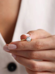 a woman's hand holding an engagement ring with a diamond on the middle finger