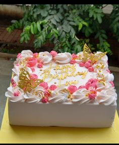 a birthday cake decorated with pink flowers and gold butterflies