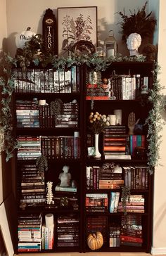 a bookshelf filled with lots of books next to a white vase and potted plant