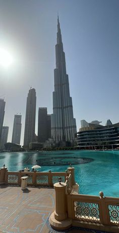 the sun shines brightly over an outdoor swimming pool in front of tall buildings and skyscrapers