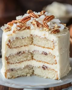 a cake with white frosting and pecans is cut in half on a plate