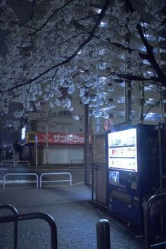 a street scene with focus on the vending machine and blossoming trees in the background