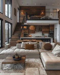 a living room filled with furniture and lots of windows next to a stair case that leads up to the second floor