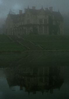 a large house sitting on top of a lush green field next to a body of water