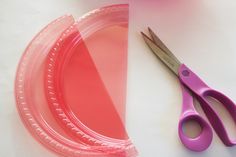 a pair of scissors sitting next to a pink container