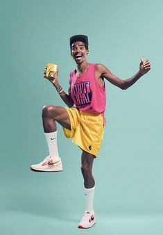 a man in a pink shirt and yellow shorts is jumping with his legs spread wide