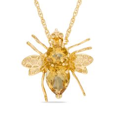 a gold bee necklace with an orange crystal stone on it's back and wings