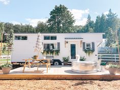 a small white house with a hot tub in the yard