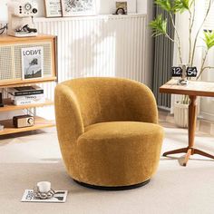 a yellow chair sitting on top of a white floor next to a table and bookshelf