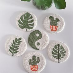 four embroidered coasters with green leaves and symbols in the shape of yin - yang