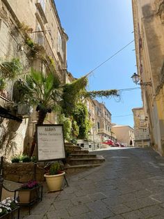 an alleyway with potted plants on either side and a sign in the middle