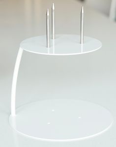 three metal nails are placed on top of a white stand that is sitting on a table