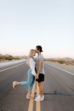 a man and woman kissing on the side of an empty road