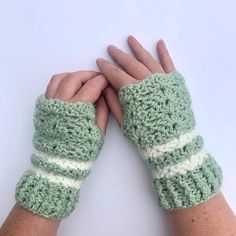 two hands wearing green and white crocheted gloves