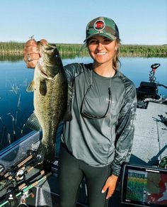 a woman holding a large fish on a boat