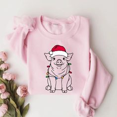 Stay warm and festive with our Festive Pig Christmas Sweatshirt! Showcasing a lovable Pig wearing a Santa hat adorned with colorful Christmas lights, this sweatshirt is a must-have for animal enthusiasts and holiday lovers. Crafted from soft, cozy fabric, it's perfect for chilly winter days, Christmas gatherings, or relaxing at home. Whether you're gifting it to a Pig mom, animal lover, or adding it to your own holiday wardrobe, this Christmas Pig Sweatshirt delivers both comfort and festive flair. Spread holiday cheer with this charming and stylish Pig Christmas Sweater! PRODUCT DESCRIPTION: Ideal for any situation, a unisex heavy blend crewneck sweatshirt is pure comfort. These garments are made from polyester and cotton. This combination helps designs come out looking fresh and beautifu Pig Christmas Shirt, Cute Winter Sweatshirt For Gift, Cute Winter Sweatshirt Gift, Cute Winter Holiday Sweatshirt, Cute Sweatshirt For Holiday Winter, Cute Winter Tops As Gift, Cute Winter Tops As A Gift, Cute Winter Holiday Tops, Pink Tops As Winter Gifts