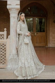 a woman in a wedding dress standing next to a pillar