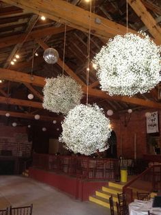 some white flowers hanging from the ceiling in a room with wooden beams and lights above them