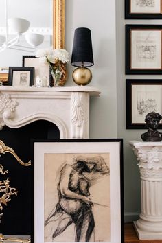 a fireplace with pictures on the mantle next to it and a framed drawing in front