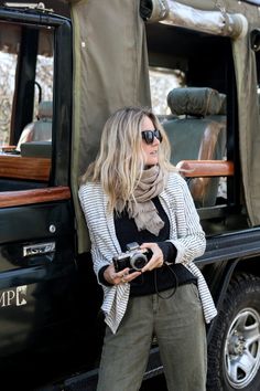 a woman standing in front of a truck holding a camera