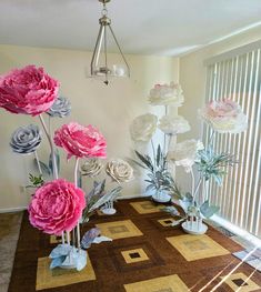 flowers are arranged in vases on the floor next to a window with vertical blinds