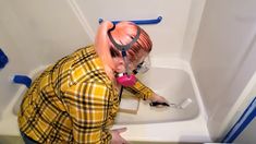 a woman with pink hair using a blow dryer on her face in the bathroom