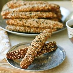 two plates with sesame seed pretzels next to a cup of coffee