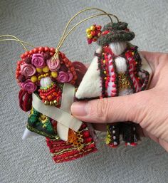 someone holding two ornaments in their hand on the carpeted floor, one is made from fabric and the other is decorated with beads