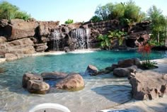 an outdoor pool with waterfall and rocks