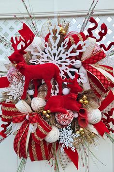 a red and white christmas wreath with reindeers, snowflakes and ornaments on the front door