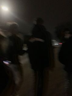 blurry photograph of people walking in the rain at night