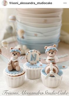 three teddy bears sitting on top of cupcakes in front of plates and cake