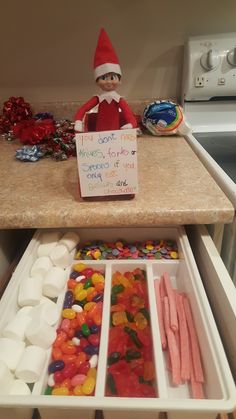 an elf is sitting on top of the counter with candy and marshmallows