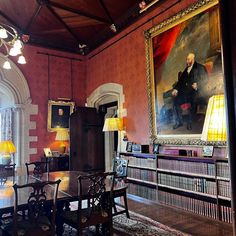 a dining room with red walls and paintings on the wall, along with wooden tables and chairs