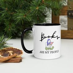 a pink and white coffee mug sitting on top of a table next to some cinnamons