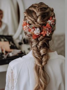 a woman with long hair and flowers in her hair is seen from the back view