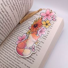 an open book with flowers on it and a cat sticker attached to the cover