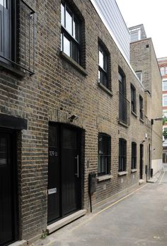 an empty street in front of a brick building with black doors and windows on both sides