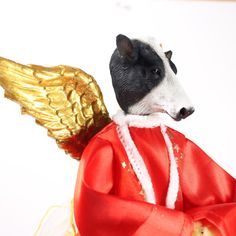 a figurine of a dog wearing a red coat and gold wings on it's back